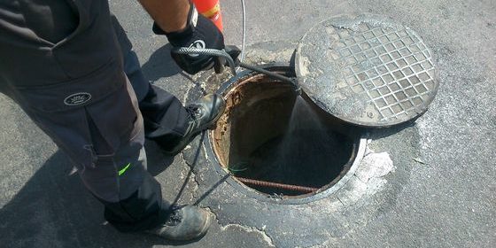 Un operario limpiando la alcantarilla