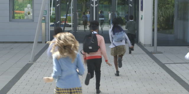 MS TU Schoolboy and schoolgirl entering into school building
